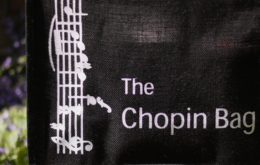 Chopin bag - these words with a sense of humor and music are on a natural sackcloth shopping bag. Green nature on a sunny day are on blurred background. Play of words. Shopping with pleasure.