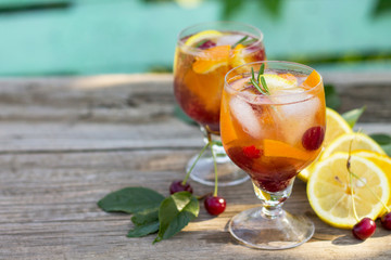 Homemade refreshing wine sangria or punch with fruits in glasses. Sangria cocktails with fresh fruits, berries and rosemary. On a wooden rustic table, with a jug and ingredients. Copy space.