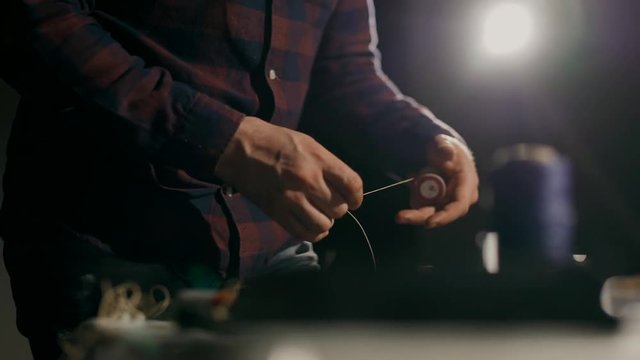 The process of manufacturing a leather wallet handmade. The craftsman measures the required length of sewing thread. Handmade leather goods.