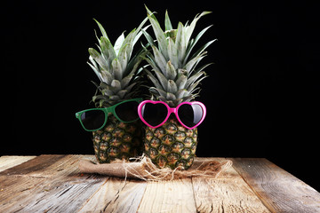 pineapple with sunglasses on rustic background.