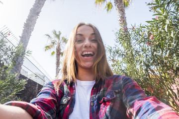 crazy nice young lady with big smile taking a selfie picture with her smart phone mobile. ready to share on the social network to their friends on line. summer style enjoying lifestyle