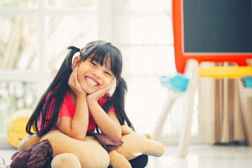 Happy asian girl sitting on kidsroom background