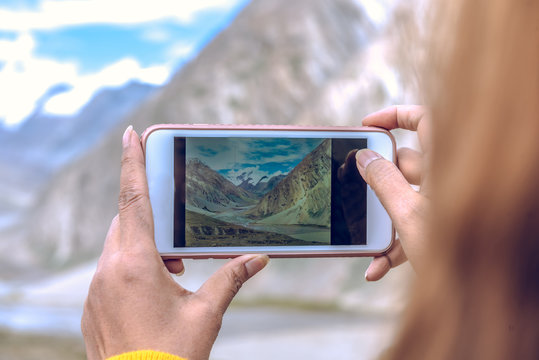 Woman using smart phone take a picture on beautiful Landscape of top Penzila valley in Karsha village, Zanskar, Ladakh, India.