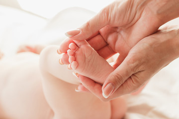 Hands of woman holds baby feet