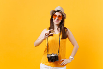 Obraz na płótnie Canvas Tourist woman in summer casual clothes, hat holding bitcoin, metal coin of golden color isolated on yellow orange background. Female traveling abroad to travel on weekends getaway. Air flight concept.