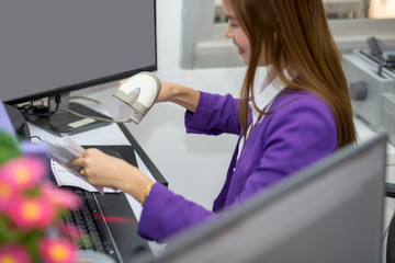 Woman is scanning the barcode on a bill with reading tool.