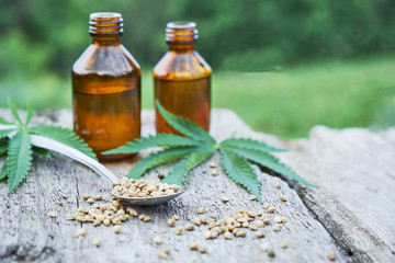 hemp leaves on wooden background, seeds, cannabis oil extracts in jars.