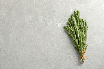 Fresh rosemary twigs tied with twine on gray table, top view