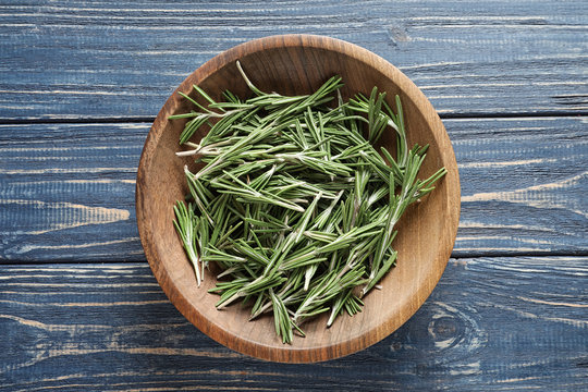 Plate with fresh rosemary twigs on wooden table, top view