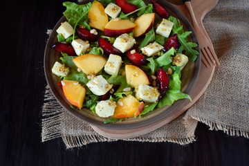 Fruit salad with arugula, plums, nectarines and soft cheese on a plate