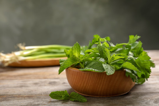Bowl with fresh herbs on wooden table