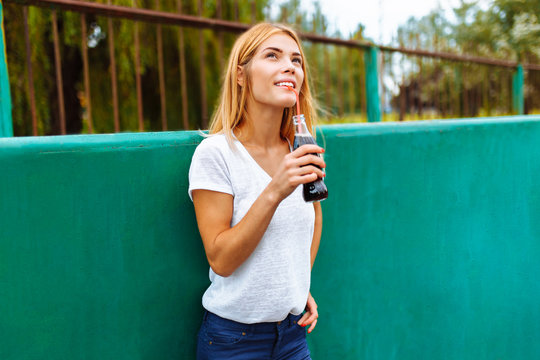 Girl with a skate in the Park, drinking a drink with a glass bottle