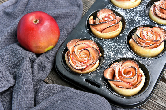 Many Apple Red Rose Tarts in muffin tray on wooden background..Apple Idea menu.
