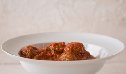 A white dish with meat balls.