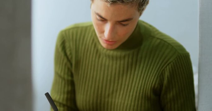 Female executive using mobile phone while writing on diary 4k