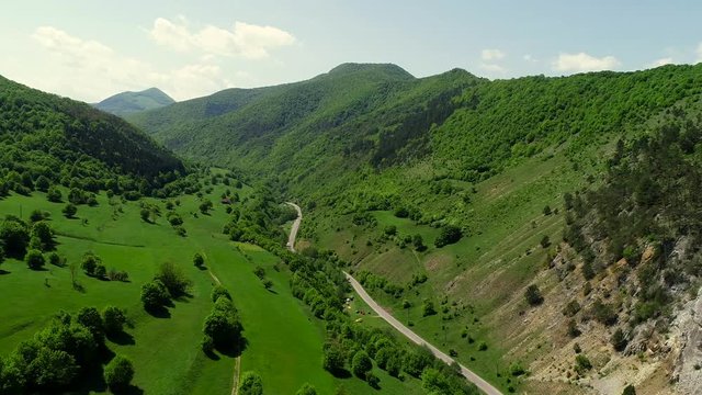 Drone flight above the road between the mountain and the hills. Green hills, Romania