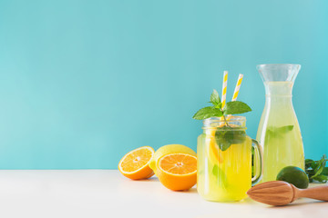Lemonade in mason jar with lemon and mint on blue. Copy space.