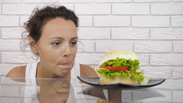 Woman with a hamburger. A hungry woman looks at a hamburger.