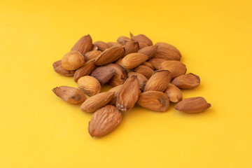 Raw almonds on a yellow background.