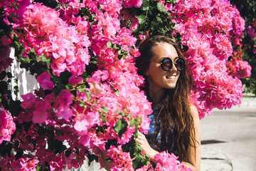 A beautiful girl in sunglasses walks in the garden of oleander