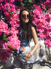 A beautiful girl in sunglasses walks in the garden of oleander