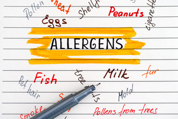 Different allergens written on lined paper and pen