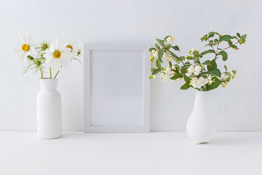 Mockup white frame and branches with green leaves in a vase