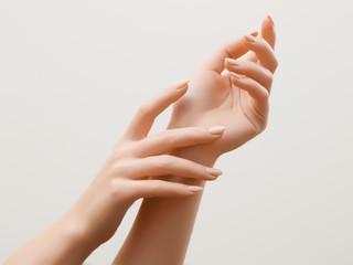 Nahaufnahmebild der Hände der schönen Frau mit hellrosa Maniküre auf den Nägeln. Hautpflege für Hände, Maniküre und Schönheitsbehandlung. Elegante und anmutige Hände mit schlanken, anmutigen Fingern