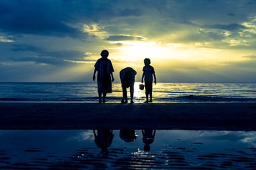 Family relaxing on the beach during sunset in tropical island .