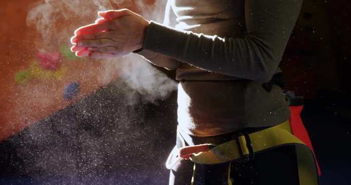 Woman dusting chalk powder from her hands at bouldering gym 4k