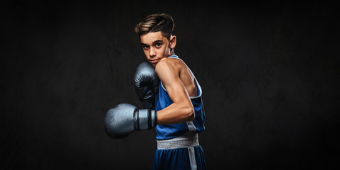 Fototapeta na wymiar Handsome young boxer during boxing exercises, focused on process. Isolated on the dark background.