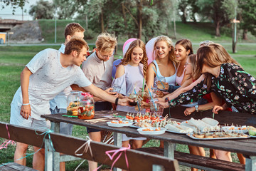 Group of happy friends having fun together celebrating a birthday at the outdoor park. Joyful...