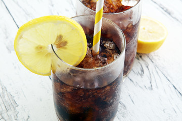 Softdrink with ice cubes, lemon and straw in glass
