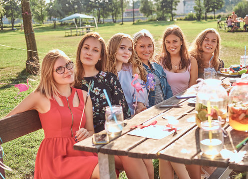 Group of happy girlfriends sitting at the table together celebrating a birthday at the outdoor park.