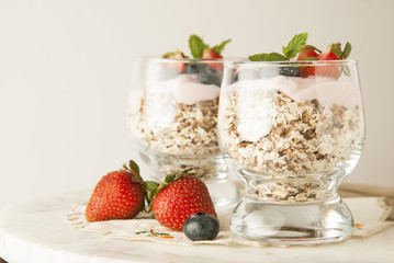 Healthy breakfast for two, oat meal with fruits: blueberry, strawberry and min, parfait in in two glasses on a rustic background. Healthy food. Isolated.