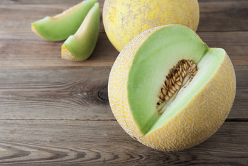 Cantaloupe yellow fresh melon isolated with sliced melon, wooden table, gray background. Summer fruits.