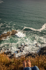 Girl with red toenails sitting on the edge of a cliff in Kinsale, Ireland
