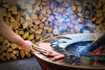 man frying sausages on a round grill