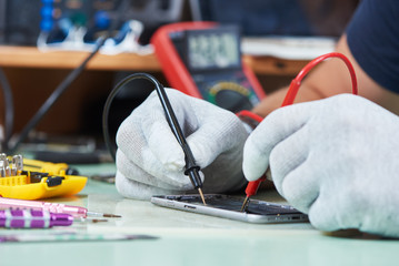smart phone repair. repairman testing electric circuit