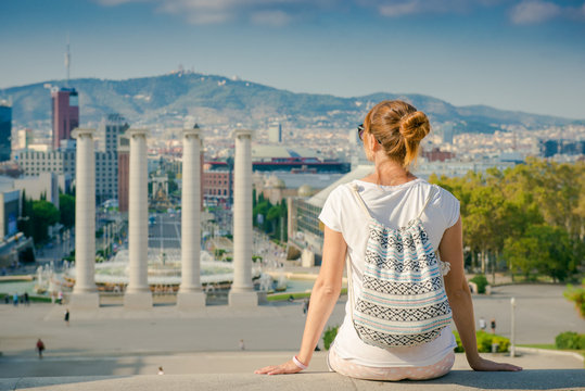 Girl tourist with a backpack looking at Barcelona. Girl sitting back and admiring the view of the city. Spain, walk around the city
