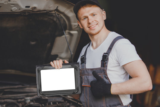 Professional car mechanic using electrnoic diagnostic equipment laptop in auto repair service.