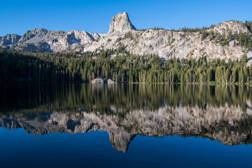 Reflection of a granite mountain crag and cliffs under a perfect blue sky in a calm lake - Crystal Crag and Lake George in the Mammoth Lakes area of California's eastern Sierra mountains