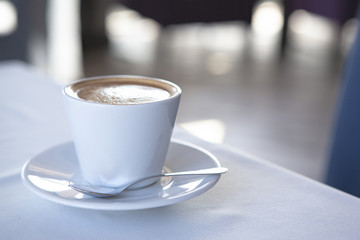 White cup of coffee on table in cafe.