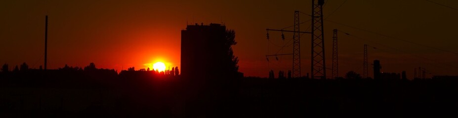 Obraz premium Black silhouette of the city and the sun
