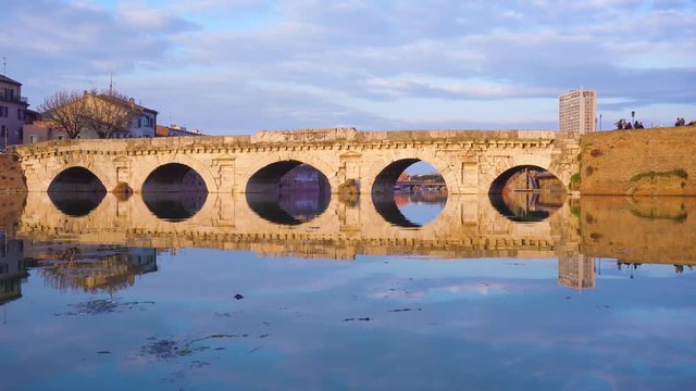 view of roman bridgereflecting in water, Rimini, Italy