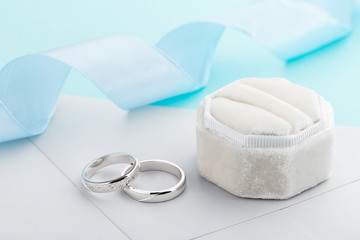 Two silver wedding rings with diamonds on blue background
