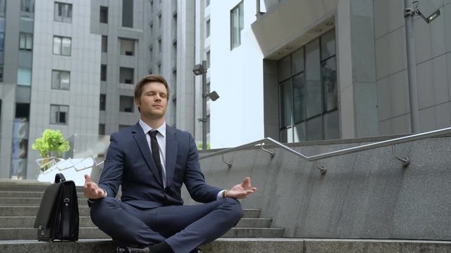Calm businessman sitting in lotus position, self-control in stressful life