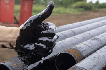oil leaking. Very dirty hand.Stain hands showing thumbs up with black oil on drill pipes...