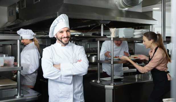 Portrait of satisfied smiling chef on restaurant kitchen
