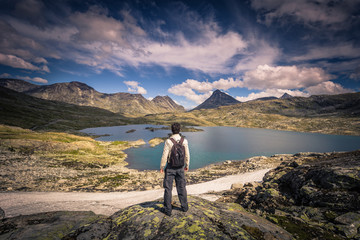 Fototapeta premium Jotunheimen National Park - July 29, 2018: Traveler in the wild mountain landscape in the Jotunheimen National Park, Norway